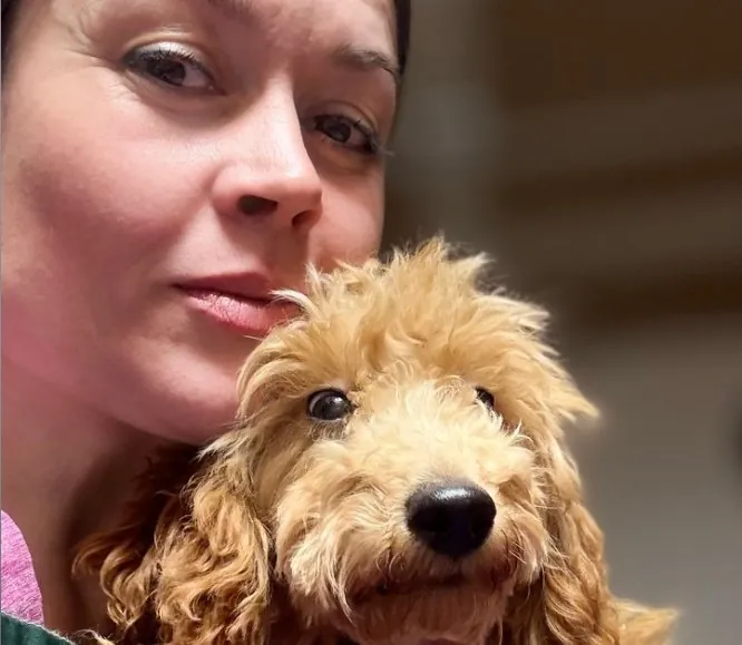 Alevtina, the groomer at The Dogs Queen, holding a curly-coated puppy